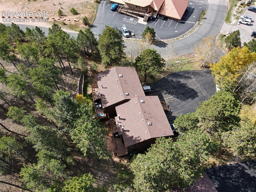 Image 40 of 50: Two-story dwelling with a brown shingle roof, surrounded by mature trees, f