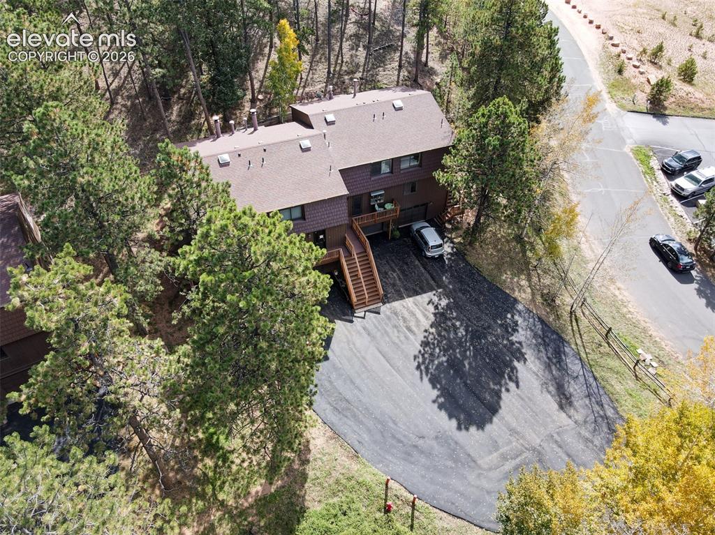 Image 41 of 50: Multi-level brown-sided residence with multiple rooflines, a dark asphalt d