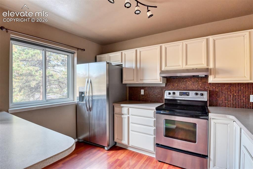 Image 8 of 50: Kitchen featuring stainless steel appliances, a tile backsplash, white cabi