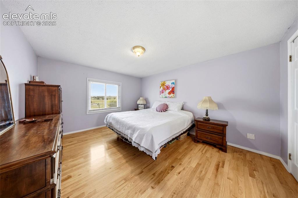 Image 16 of 40: Master bedroom as is featuring wood-finish flooring, a white trim window, a