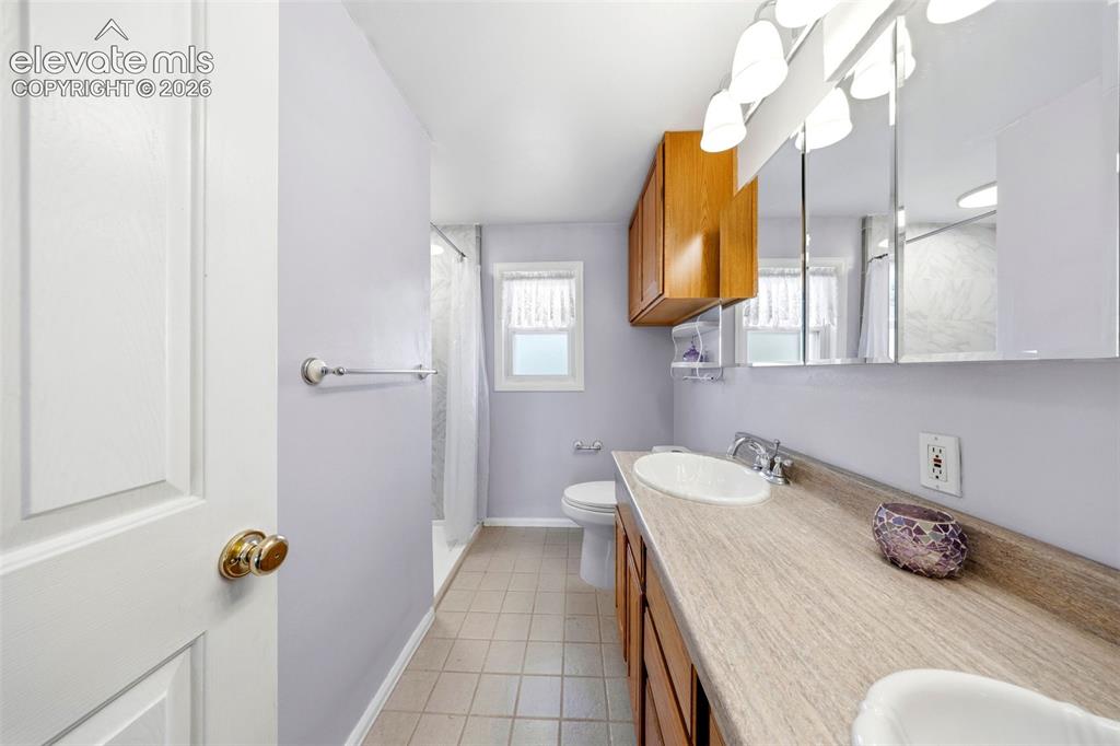 Image 18 of 40: Bathroom vanity with dual oval sinks and cabinetry