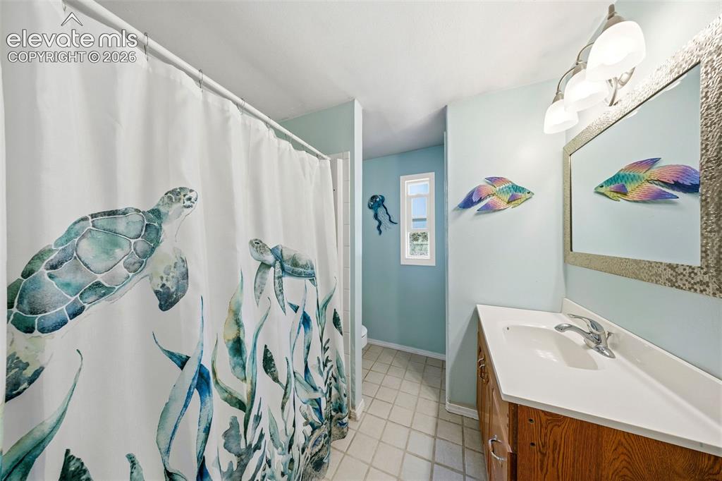 Image 27 of 40: Guest bathroom featuring a vanity with a white countertop and wood-finish c