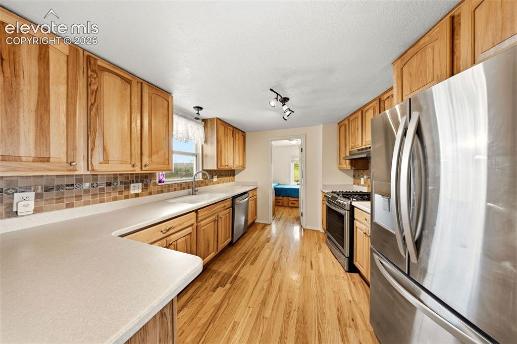 Image 8 of 40: U-shaped kitchen featuring light wood cabinetry, light-toned countertops, a