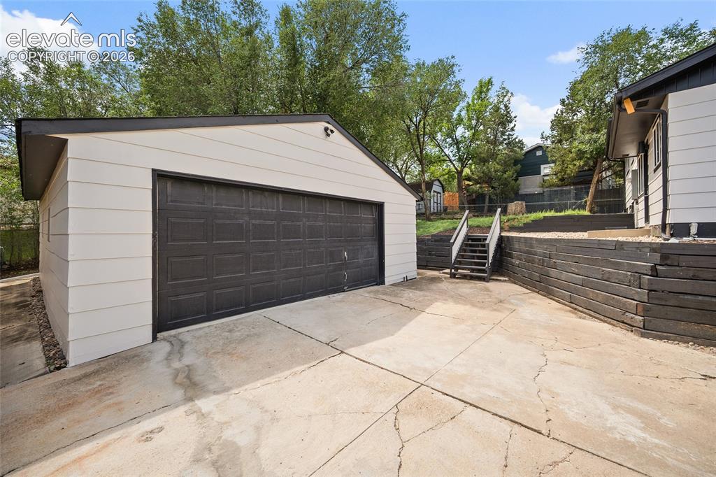 Image 10 of 49: Detached garage with paneled door and light-toned siding