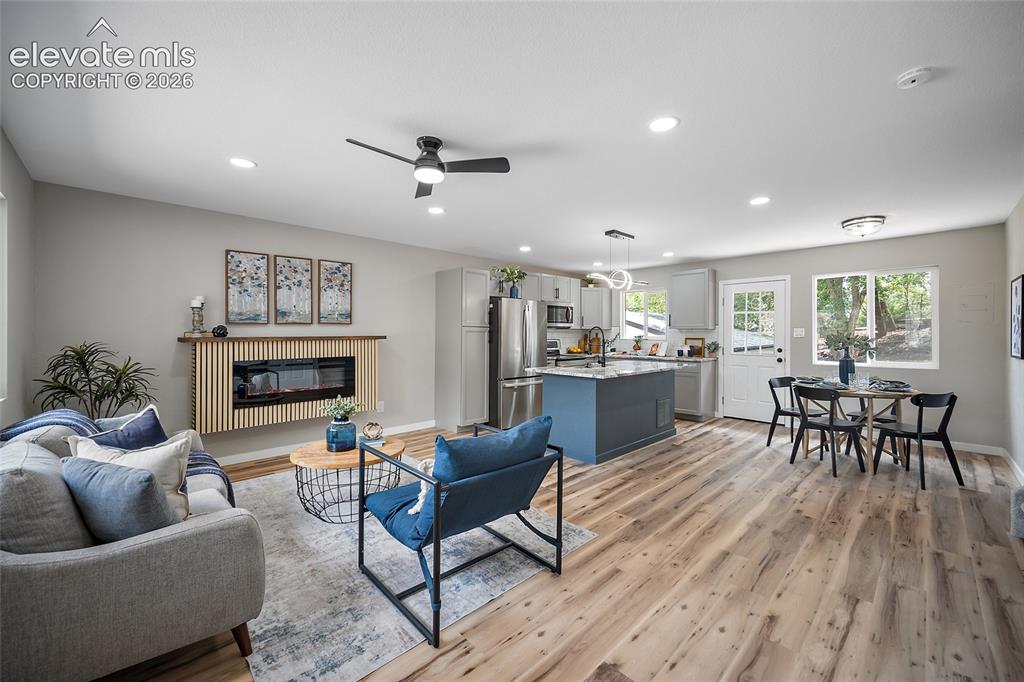 Image 11 of 49: Open-concept living space with wood-finish flooring, recessed lighting, and