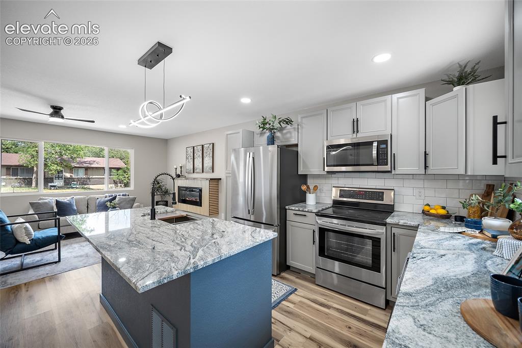 Image 17 of 49: Kitchen featuring a large island with sink, stainless steel appliances, lig