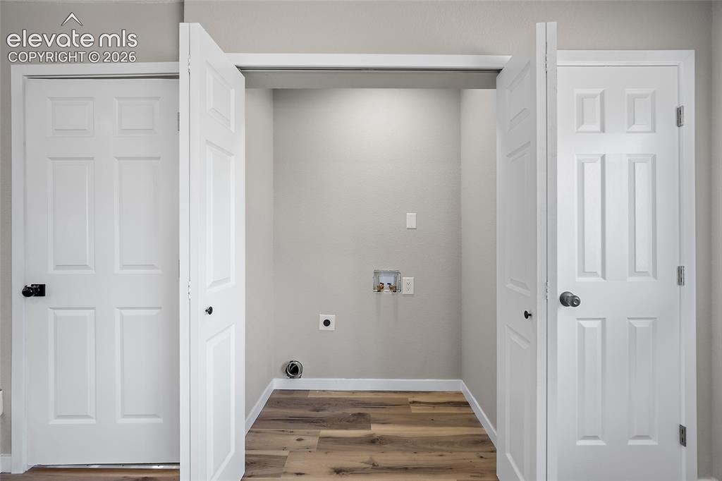 Image 21 of 49: Dedicated laundry alcove with wood-finish flooring, washer/dryer hookups, a
