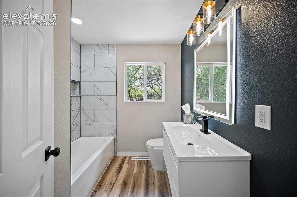 Image 25 of 49: Contemporary vanity with an integrated sink, illuminated mirror, and modern