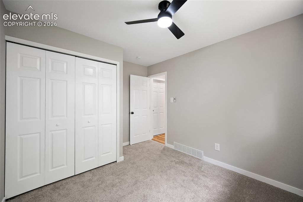 Image 27 of 49: Plush carpet flooring with light gray wall paint, a black ceiling fan, and 