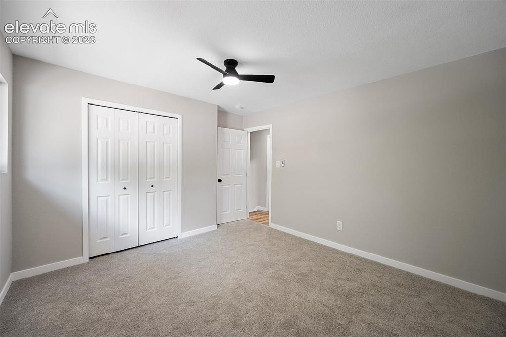 Image 29 of 49: Plush carpeting, white trim, bifold closet doors, and a ceiling fan