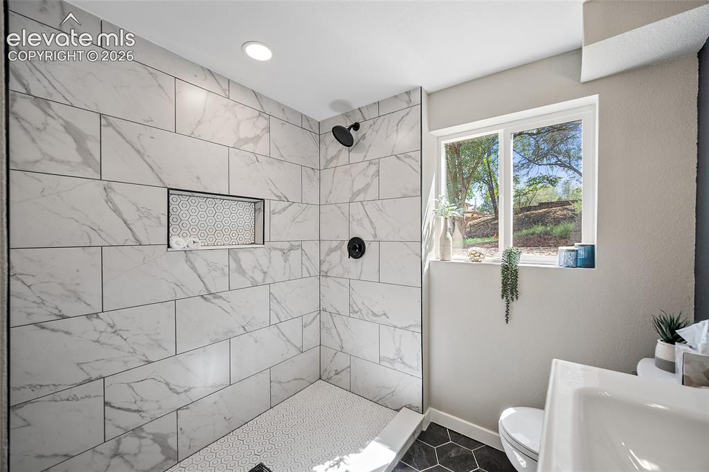 Image 30 of 49: Walk-in shower with large format marble-look tile, matte black fixtures, an