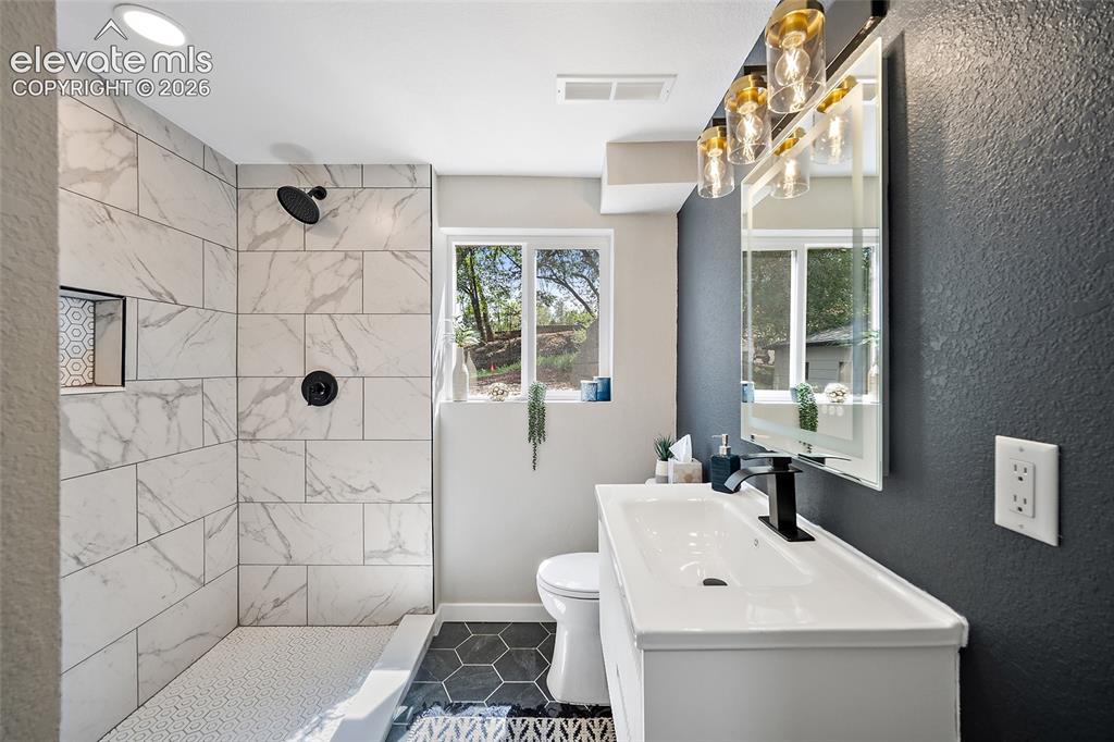 Image 31 of 49: Large format marble-look tile shower with a recessed niche, black fixtures,