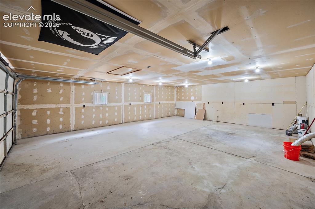Image 37 of 49: Attached garage with an overhead door, concrete flooring, and multiple ceil