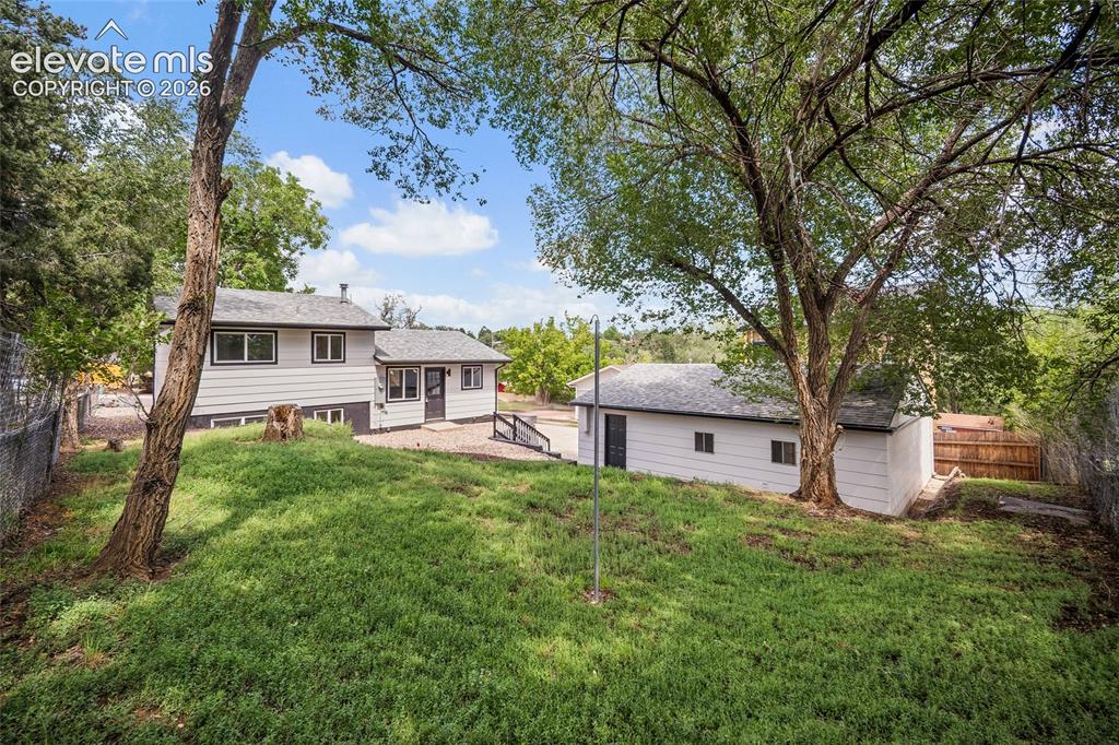 Image 40 of 49: Expansive grassy area with mature trees, detached accessory structure, and