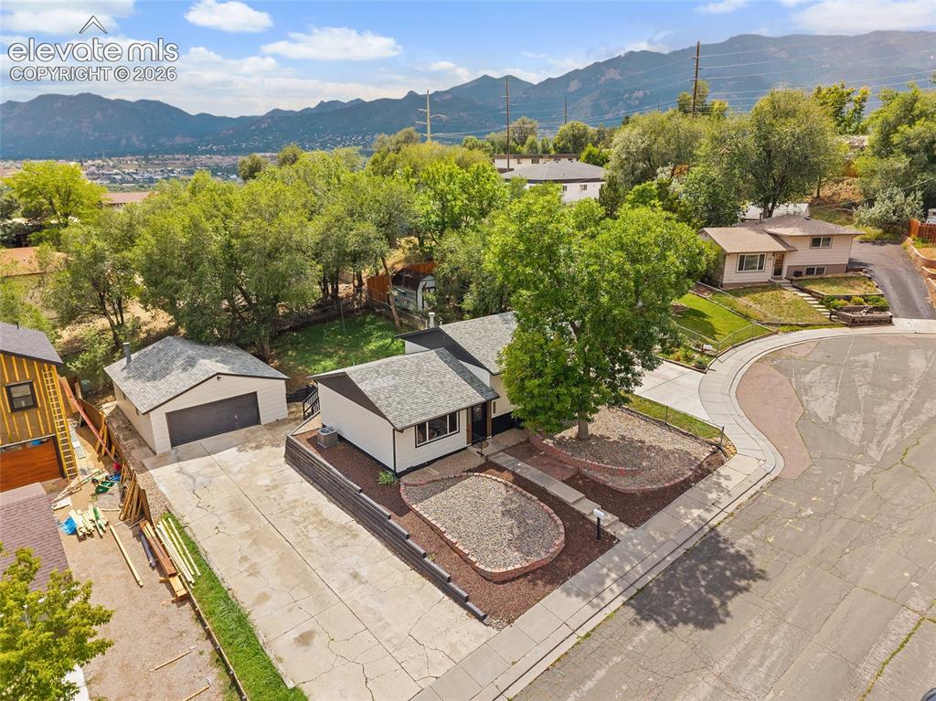 Image 44 of 49: Single-story residence with a detached garage, concrete driveway, and lands
