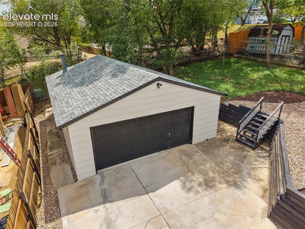 Image 45 of 49: Detached garage with a dark gray overhead door and light-colored siding