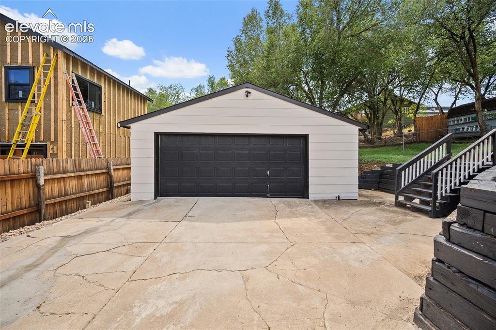 Image 9 of 49: Detached garage with horizontal siding, a gabled roof, and a dark sectional