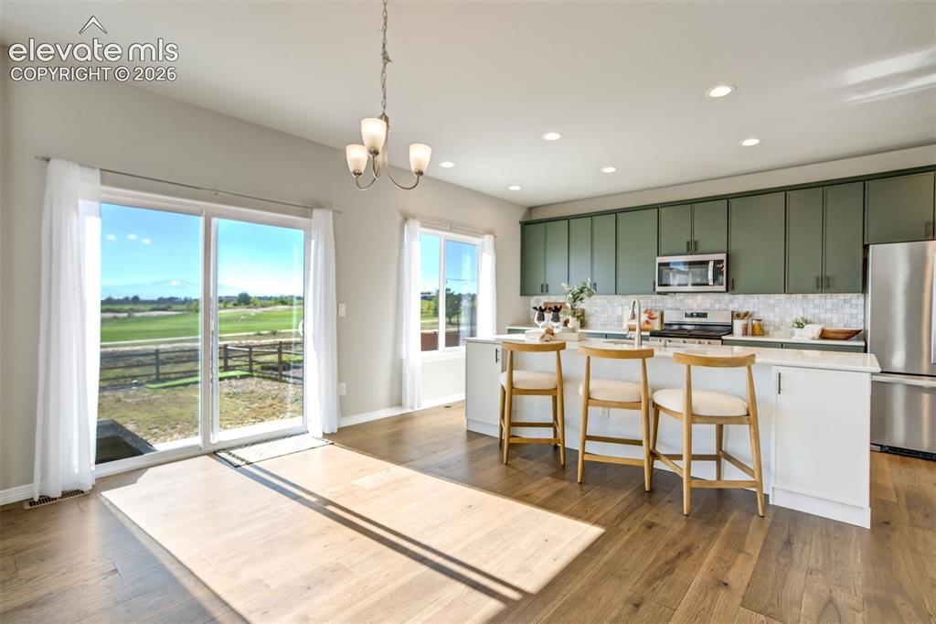 Image 10 of 47: Open-concept living space with wood-finish flooring, a sliding glass door, 