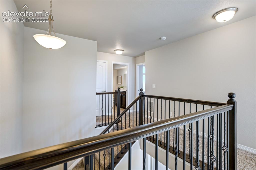 Image 17 of 47: Wrought iron balusters, dark wood handrail, recessed ceiling lighting, pend