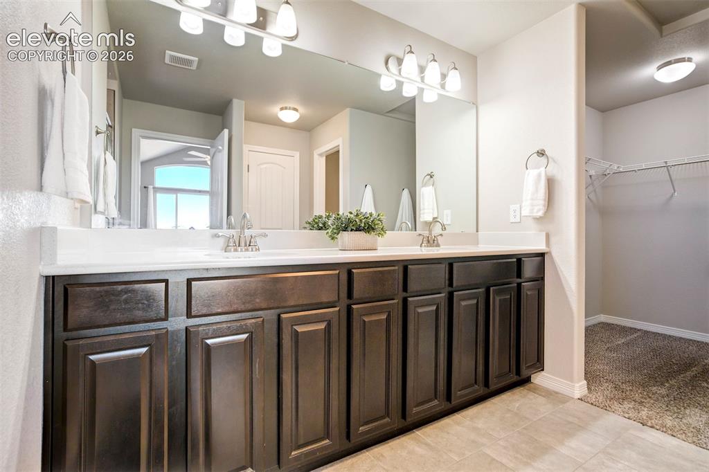 Image 24 of 47: Dual vanity with dark wood-finish cabinetry, integrated sinks, and polished