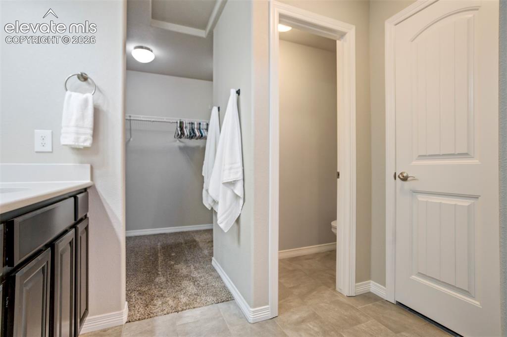 Image 25 of 47: Vanity with white countertop, dark wood-finish cabinetry, and brushed nicke