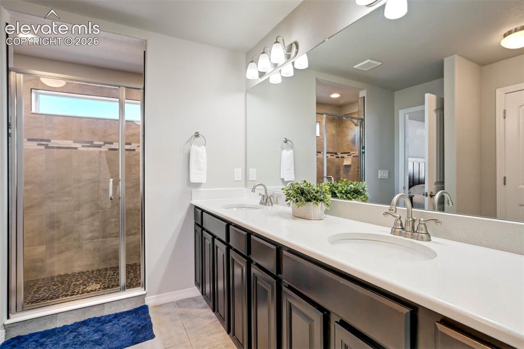 Image 26 of 47: Double vanity with undermount sinks and chrome faucets, large mirror, dark