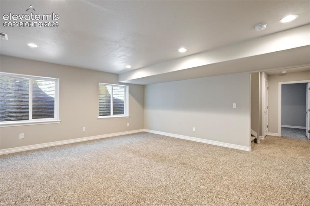 Image 34 of 47: Recessed lighting, light-colored carpeting, two egress windows, neutral wal