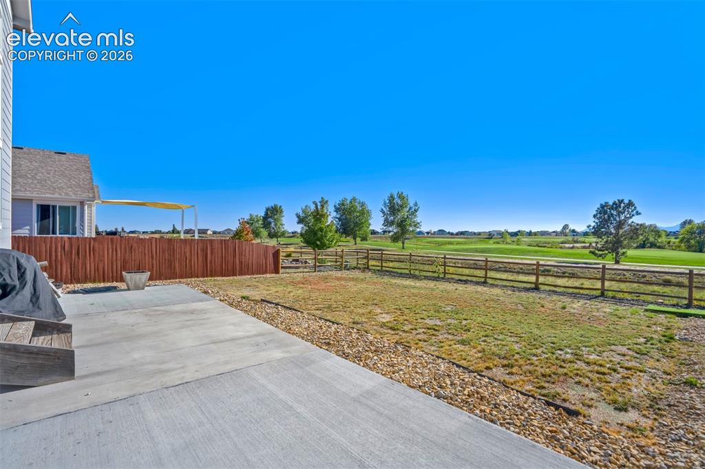 Image 42 of 47: Expansive concrete patio with a gravel border, wood privacy fence, and a di