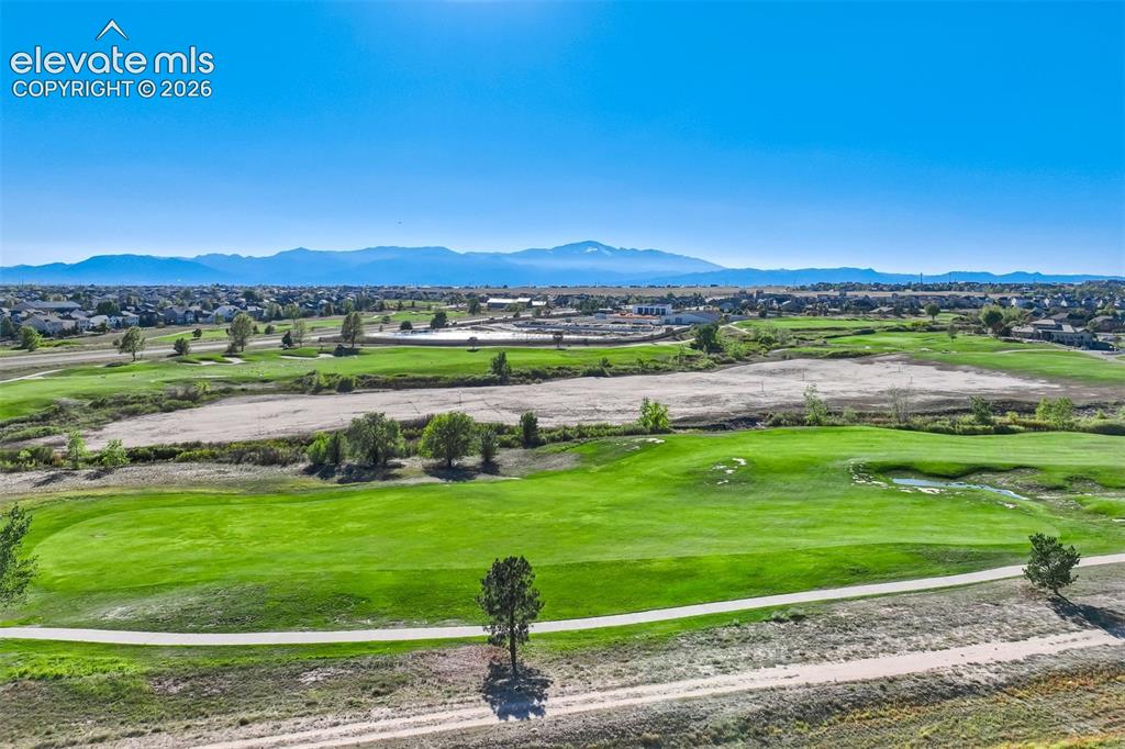 Image 44 of 47: Expansive green space featuring golf course fairways, distant mountain rang