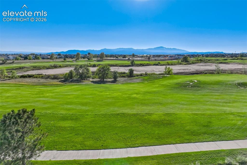Image 47 of 47: Expansive green golf course with a paved path, surrounded by distant reside