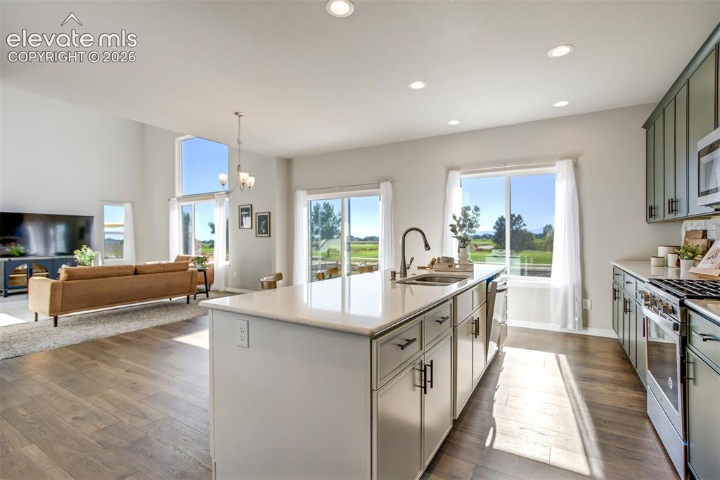 Image 5 of 47: Expansive kitchen island with a built-in sink, recessed lighting, wood-fini