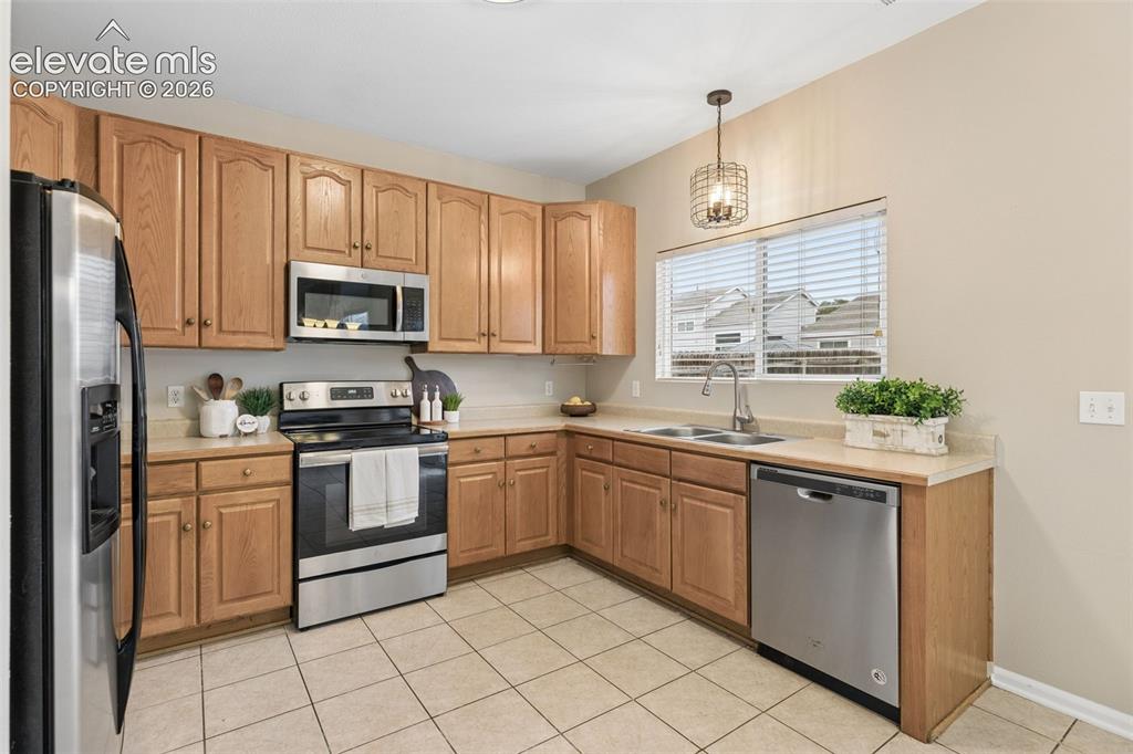 Image 10 of 26: Kitchen featuring wood cabinetry, stainless steel appliances, tile flooring