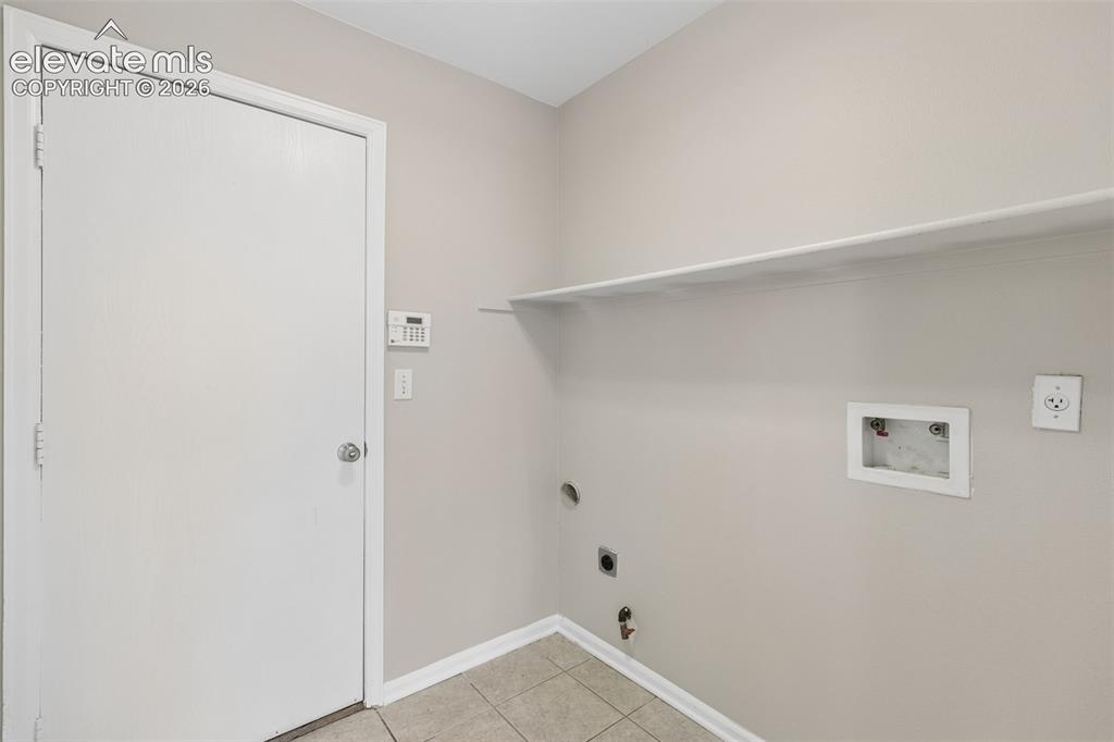 Image 14 of 26: Utility space featuring neutral wall paint, tiled flooring, an overhead bui