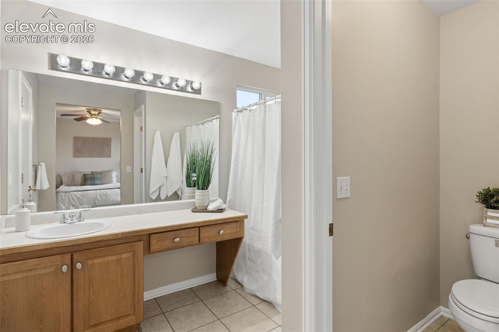 Image 17 of 26: Bathroom featuring a vanity with wood-finish cabinetry, integrated countert