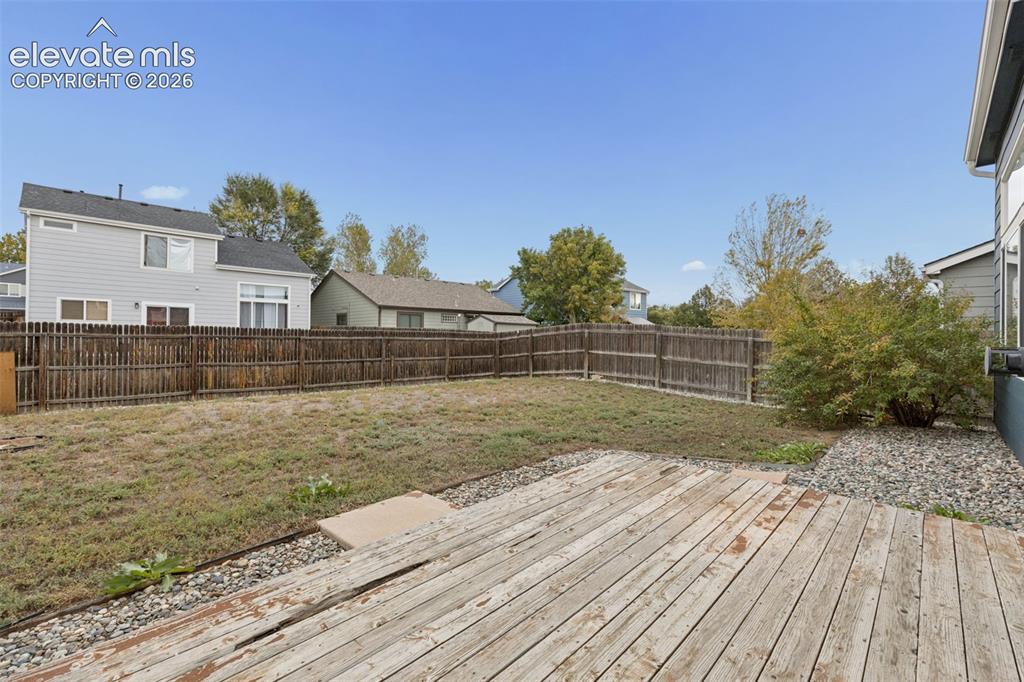 Image 24 of 26: Rear yard featuring a wood deck, perimeter wood fencing, and gravel hardsca