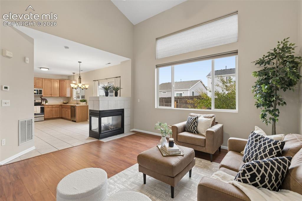 Image 6 of 26: Vaulted ceilings, corner fireplace with tile surround, wood-finish flooring