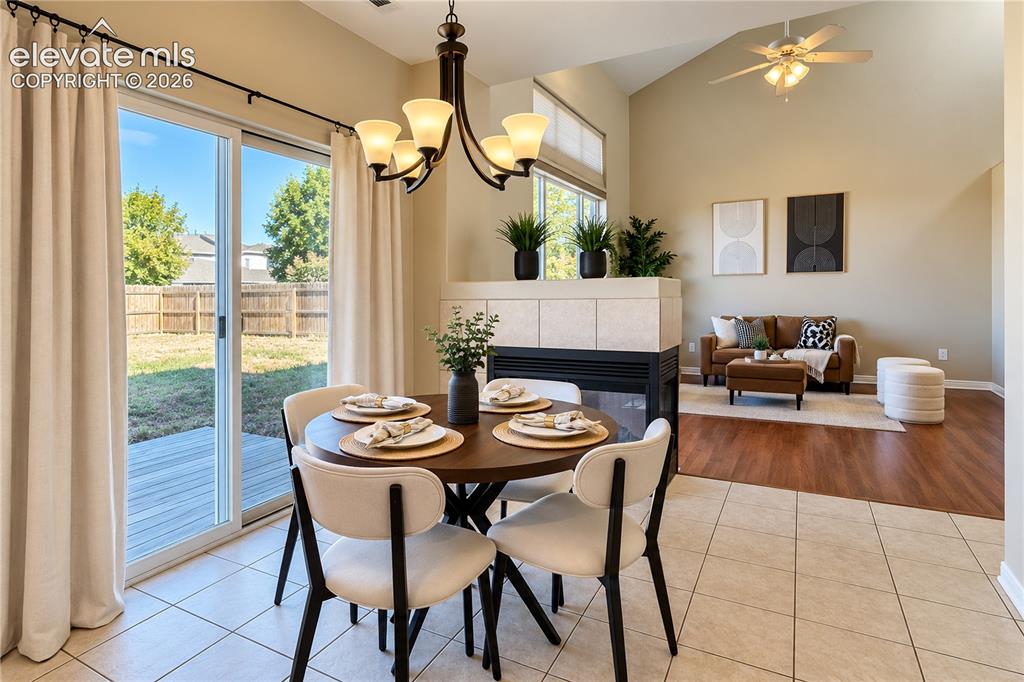 Image 7 of 26: Vaulted ceiling with integrated ceiling fan, dual-sided fireplace with tile