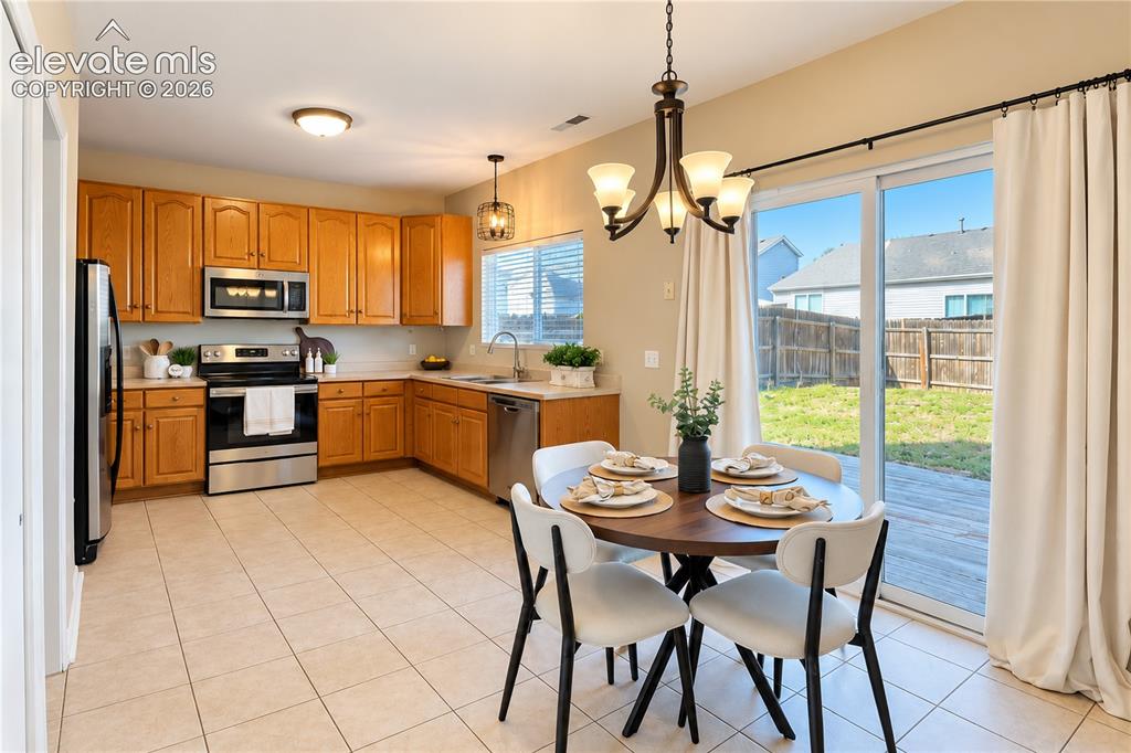 Image 8 of 26: Kitchen featuring natural wood cabinetry, stainless steel appliances, ceram