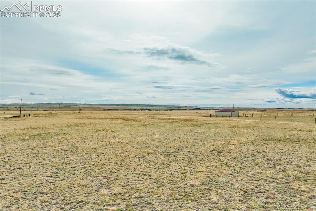 Image 6 of 25: View of yard with an outdoor structure, fence, and a rural view