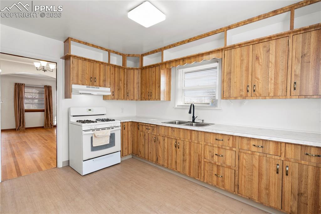 Image 15 of 21: Kitchen featuring white range with gas cooktop, light countertops, light wo
