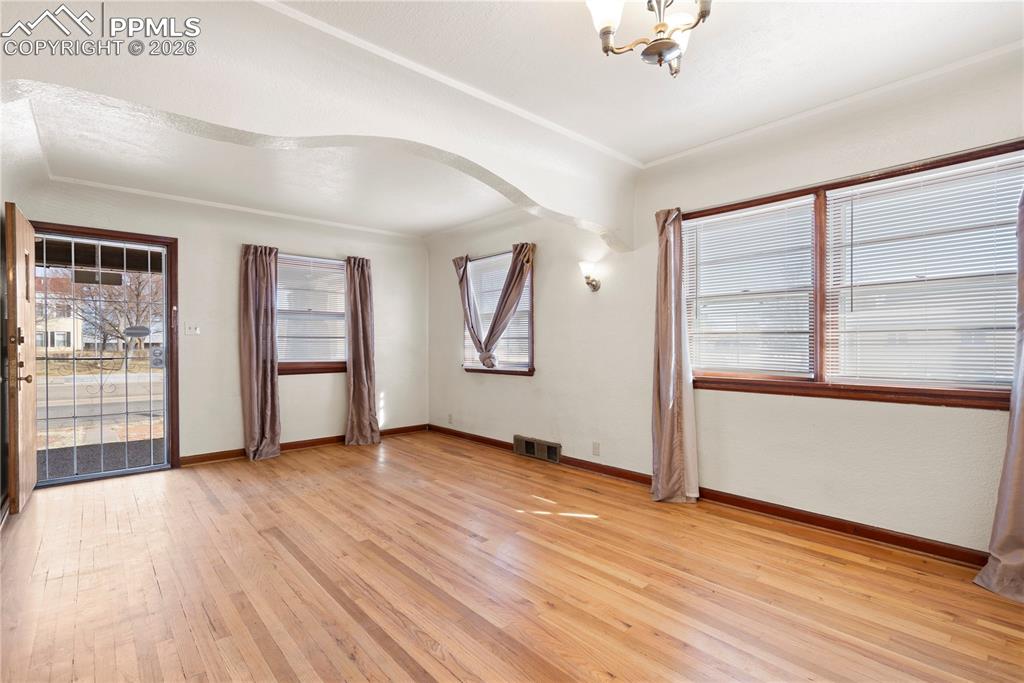 Image 16 of 21: Spare room featuring light wood finished floors, arched walkways, and suspe