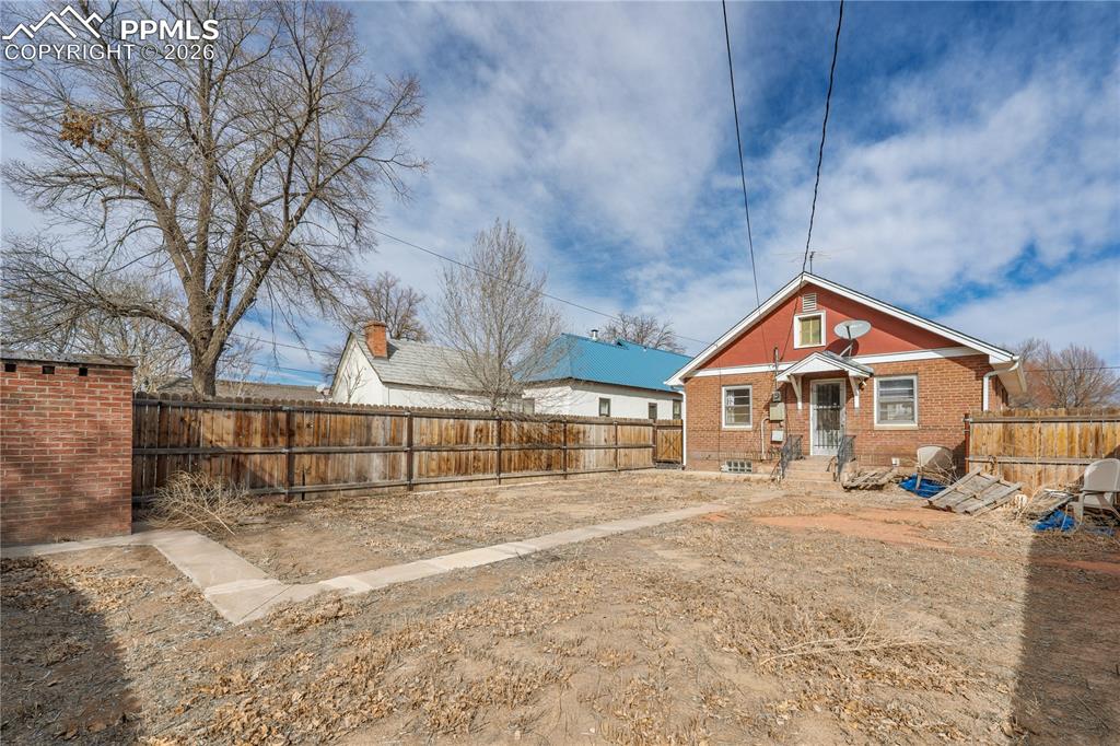 Image 19 of 21: Back of property with a fenced backyard and brick siding