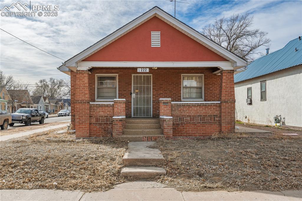 Image 2 of 21: Bungalow-style home with covered porch and brick siding
