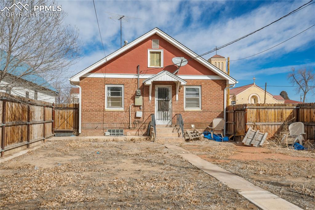 Image 20 of 21: Back of property featuring brick siding, a fenced backyard, and a gate