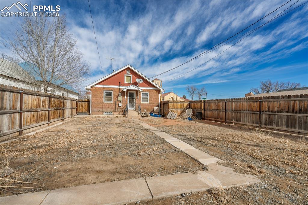 Image 21 of 21: Back of property with brick siding and a fenced backyard