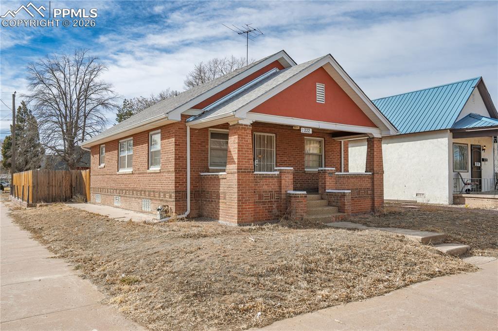 Image 3 of 21: View of front of house featuring crawl space, brick siding, and a porch
