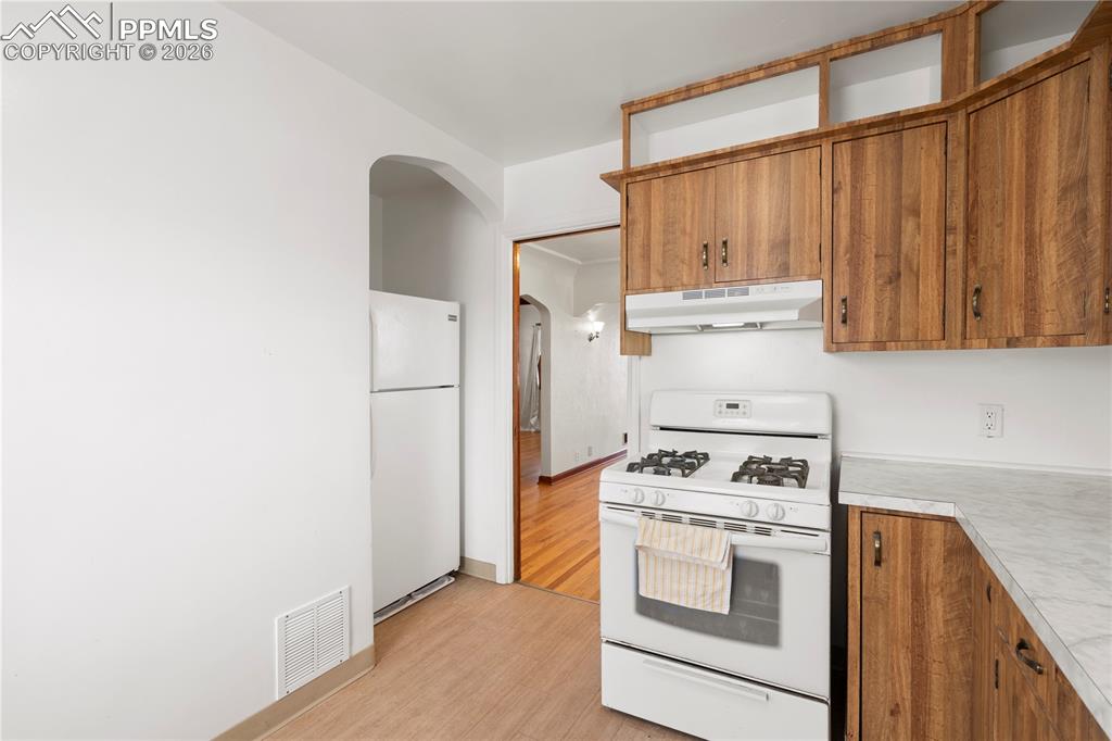 Image 7 of 21: Kitchen with white appliances, light countertops, wood finish cabinets, arc