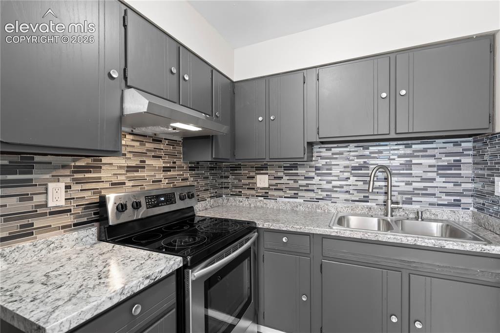 Image 13 of 32: Kitchen featuring grey cabinetry, stainless steel appliances, a tile backsp
