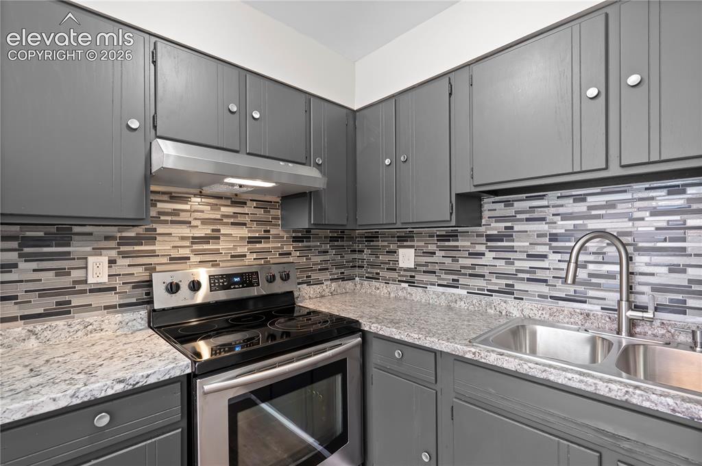 Image 14 of 32: Kitchen featuring dark gray cabinetry with circular silver hardware, light 