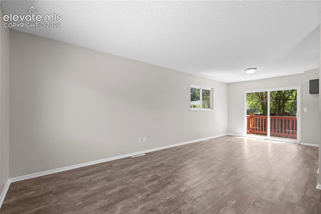Image 15 of 32: Spacious room featuring wood-finish flooring, a sliding glass door to a dec